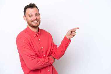Beyaz arka planda izole edilmiş genç Brezilyalı adam parmağını yana doğru gösteriyor.