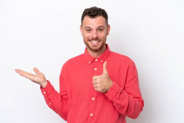 Beyaz arka planda izole edilmiş genç Brezilyalı bir adam. Kopyalama alanı hayali bir şey tutuyor. Bir ilan vermek için.