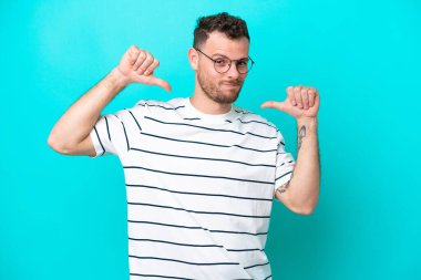 Genç Brezilyalı adam mavi arka planda soyutlanmış gururlu ve kendini beğenmiş.