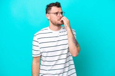 Mavi arka planda izole edilmiş genç Brezilyalı adam biraz gergin.