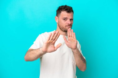 Mavi arka planda izole edilmiş genç Brezilyalı adam sinirleri öne doğru geriliyor.