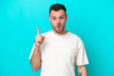 Mavi arka planda izole edilmiş genç Brezilyalı bir adam parmağını kaldırarak çözümü anlamaya çalışıyor.