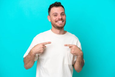 Mavi arka planda yalıtılmış Brezilyalı genç bir adam. Sürpriz bir yüz ifadesi var.