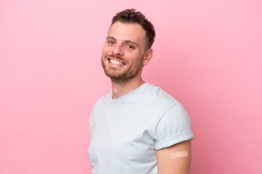 Pembe arka planda izole edilmiş yara bandı takan genç Brezilyalı adam çok gülümsüyor.