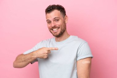 Pembe arka planda izole edilmiş yara bandı takan genç Brezilyalı adam.