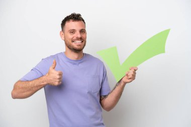 Beyaz arka planda izole edilmiş genç Brezilyalı bir adam başparmağıyla bir onay simgesi tutuyor.