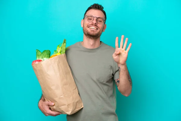 Young Brazilian Man Holding Grocery Shopping Bag Isolated Blue Background — Φωτογραφία Αρχείου