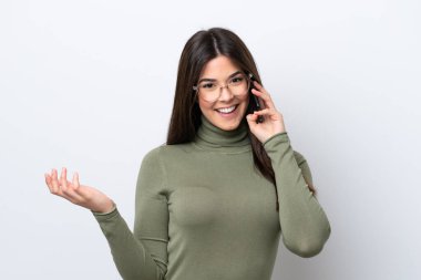 Beyaz arka planda izole edilmiş genç Brezilyalı bir kadın cep telefonuyla sohbet ediyor.