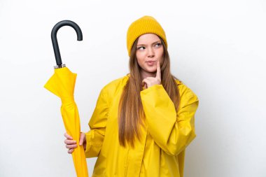 Yağmura dayanıklı ceketi ve şemsiyesi olan beyaz arka planda izole edilmiş beyaz bir kadın.