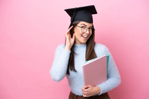 Młoda Studentka Brazylijka Nosi Kapelusz Różowym Tle Słuchając Czegoś Kładąc — Zdjęcie stockowe