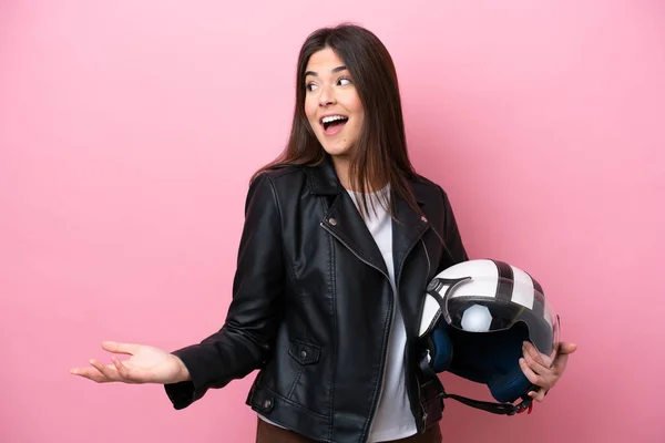 若いですブラジル人女性とともにオートバイヘルメット隔離ピンクの背景に驚きの表情で横を見ながら — ストック写真