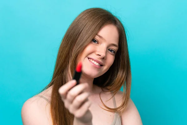 Mujer Joven Caucásica Aislada Sobre Fondo Azul Sosteniendo Lápiz Labial — Foto de Stock