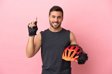 Pembe arka planda izole edilmiş genç bisikletçi harika bir fikre işaret ediyor.