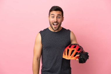 Genç bisikletçi, pembe arka planda izole edilmiş ve yüzünde sürpriz bir ifade var.