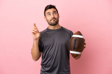 Rugby oynayan beyaz bir adam pembe arka planda izole edilmiş, şans diliyor.