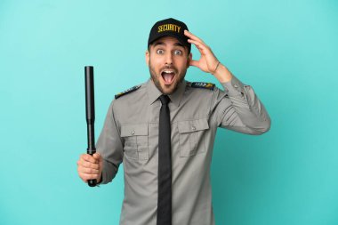 Genç güvenlik görevlisi mavi arka planda, sürpriz bir ifadeyle izole edilmiş.