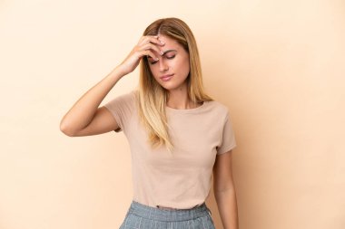Sarışın Uruguaylı kız bej arka planda baş ağrısı ile izole edilmiş.