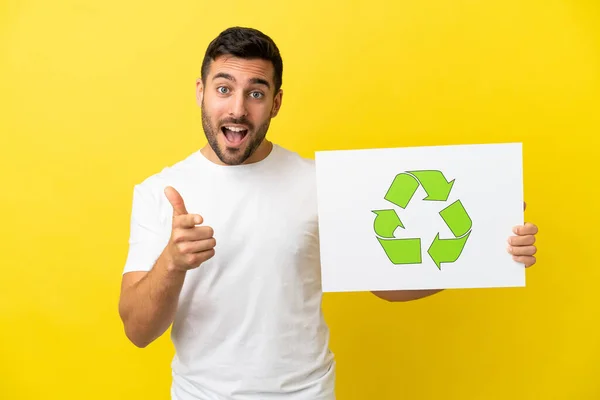 Mladý Pohledný Běloch Izolovaný Žlutém Pozadí Drží Plakát Ikonou Recyklace — Stock fotografie