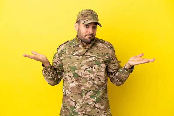 Military Man Isolated Yellow Background Having Doubts While Raising Hands — Foto de Stock
