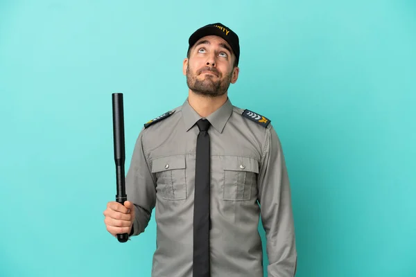 Young security man isolated on blue background and looking up