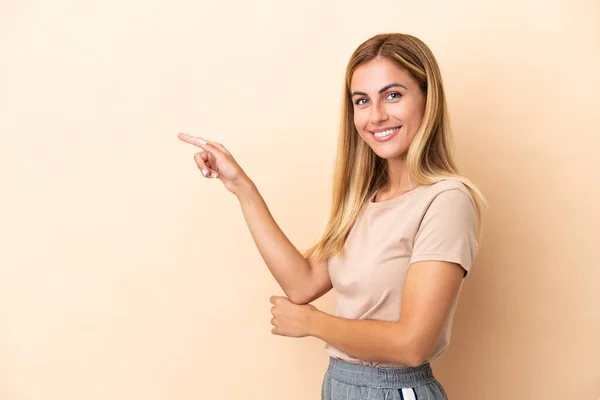 Blond Uruguayaans Meisje Geïsoleerd Beige Achtergrond Wijzend Vinger Naar Zijkant — Stockfoto