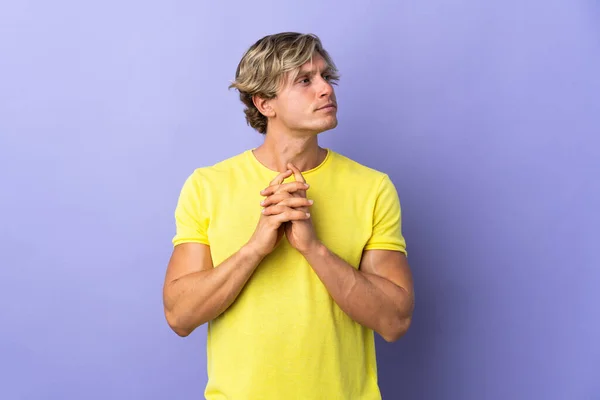 English man over isolated purple background scheming something