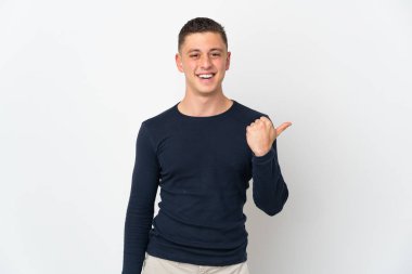 Beyaz arka planda izole edilmiş genç beyaz bir adam bir ürün sunmak için kenarı işaret ediyor.