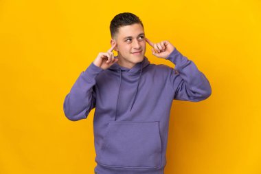 Sarı arka planda soyutlanmış genç beyaz bir adamın şüpheleri ve düşünceleri var.