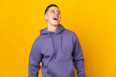 Sarı arka planda izole edilmiş genç beyaz adam gülüyor.