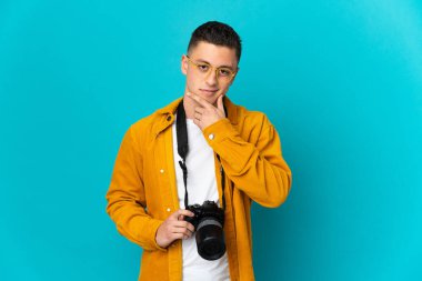 Young  caucasian photographer man isolated on blue background thinking