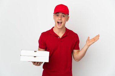Pizza delivery man with work uniform picking up pizza boxes isolated on white background with shocked facial expression