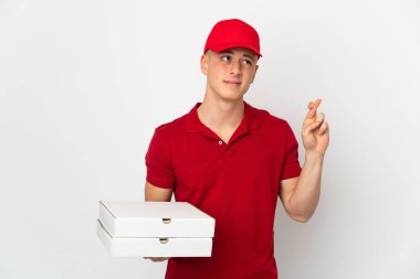 Pizza delivery man with work uniform picking up pizza boxes isolated on white background with fingers crossing and wishing the best
