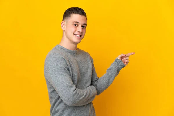 Νεαρός Καυκάσιος Άνδρας Απομονωμένος Κίτρινο Φόντο Δείχνοντας Δάχτυλο Στο Πλάι — Φωτογραφία Αρχείου
