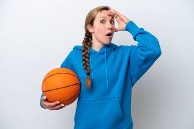 Beyaz arka planda basketbol oynayan beyaz tenli genç bir kadın yan tarafa bakarken sürpriz jest yapıyor.