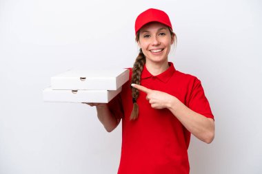 İş üniformalı bir pizzacı kadın beyaz arka planda izole edilmiş pizza kutularını topluyor ve bir ürün sunmak için yan tarafa bakıyor.