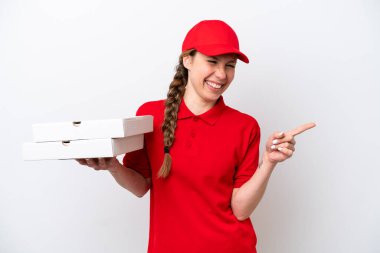 İş üniformalı bir pizzacı kadın beyaz arka planda izole edilmiş pizza kutularını topluyor. Parmakla göstererek bir ürün sunuyor.