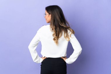 Mor arka planda izole edilmiş genç beyaz kadın arka planda ve yan bakıyor.