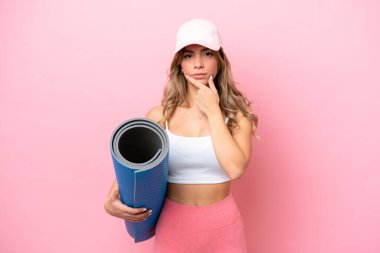 Genç sporcu kadın, elinde minderle yoga derslerine gidiyor.