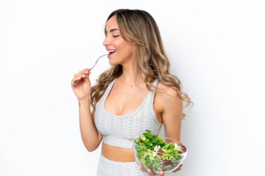 Beyaz arka planda izole edilmiş beyaz bir kadın elinde bir kase salata ile ona mutlu bir ifadeyle bakıyor.
