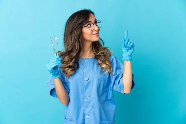女牙医把工具放在蓝色的背景上 这说明了一个伟大的想法 — 图库照片