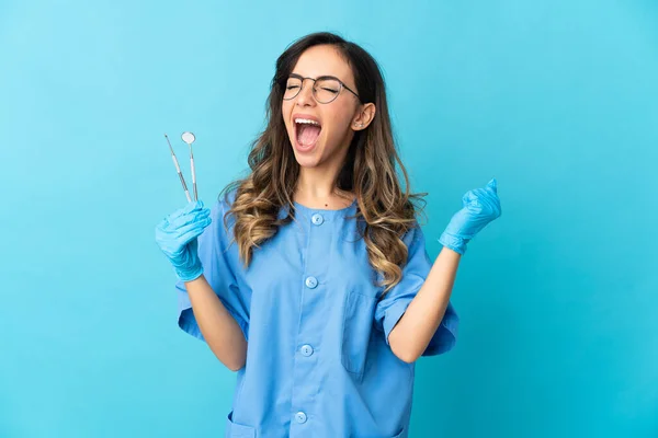 Zahnärztin Hält Werkzeug Über Sich Auf Blauem Hintergrund Und Feiert — Stockfoto