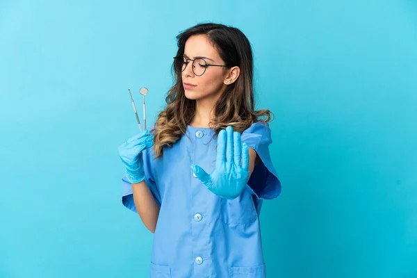 Γυναίκα Οδοντίατρος Κρατώντας Εργαλεία Πάνω Απομονωμένο Μπλε Φόντο Κάνοντας Χειρονομία — Φωτογραφία Αρχείου