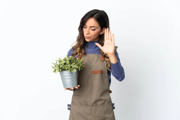 园丁女孩抱着一株因白色背景而被隔离的植物 做了停止手势 并感到失望 — 图库照片