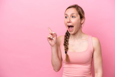 Pembe arka planda izole edilmiş genç beyaz kadın çözümü bulmak için parmağını kaldırıyor.