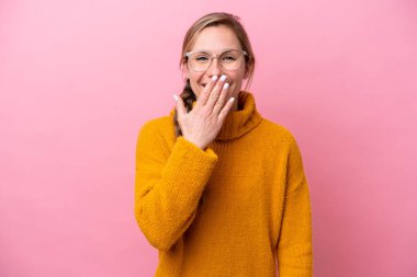 Pembe arka planda izole edilmiş genç beyaz kadın mutlu ve gülümsüyor.