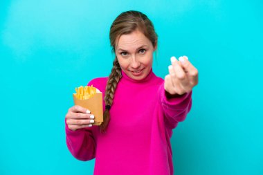 Elinde kızarmış cips tutan beyaz bir kadın. Mavi arka planda izole edilmiş. Para hareketi yapıyor.