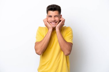 Beyaz arka planda izole edilmiş genç beyaz adam hayal kırıklığına uğramış ve kulaklarını kapatmış.