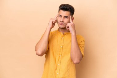 Beyazlı genç bir adam bej arka planda izole edilmiş. Şüpheleri ve düşünceleri var.