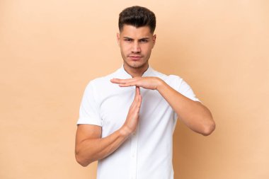 Beyazlı genç bir adam bej arka planda izole edilmiş.