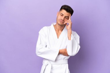 Kafkasyalı genç bir adam mor arka planda baş ağrısıyla karate yapıyor.
